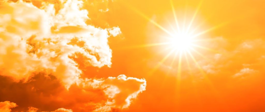 Bright sun shining through orange and yellow clouds with strong sun rays