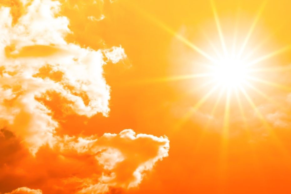 Bright sun shining through orange and yellow clouds with strong sun rays
